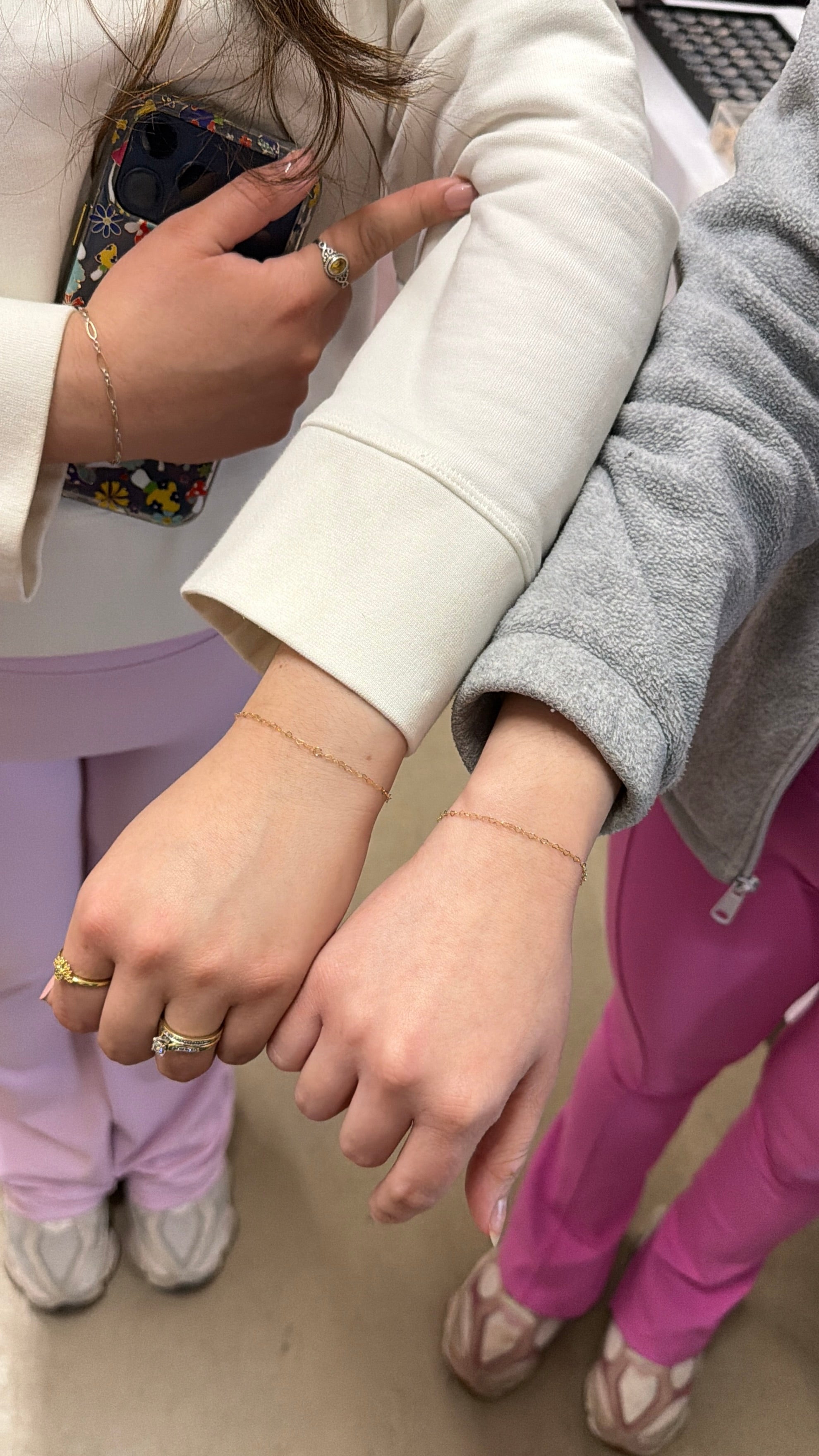 Two children holding hands, one wearing a white coat and the other in pink pants.